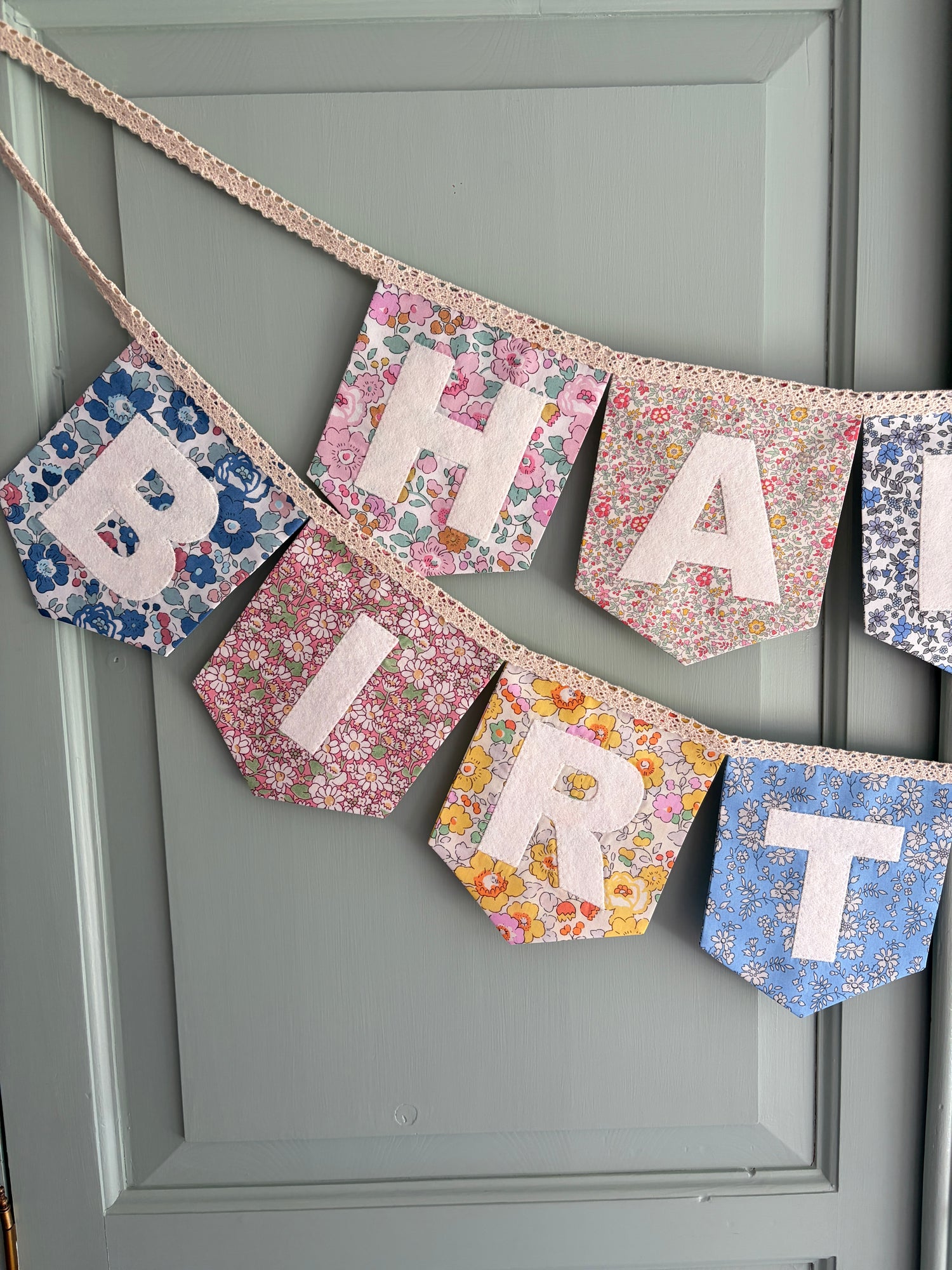 Close up of Liberty London Floral Print Bunting with ivory felt happy birthday applique letters