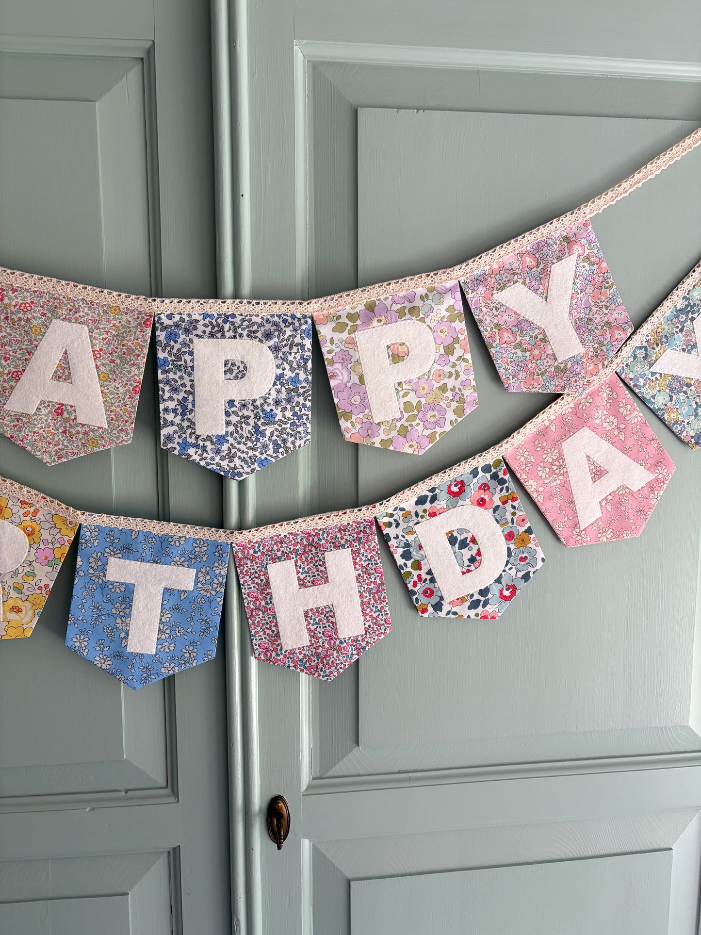 Close up of Liberty London Floral Print Bunting with ivory felt happy birthday applique letters