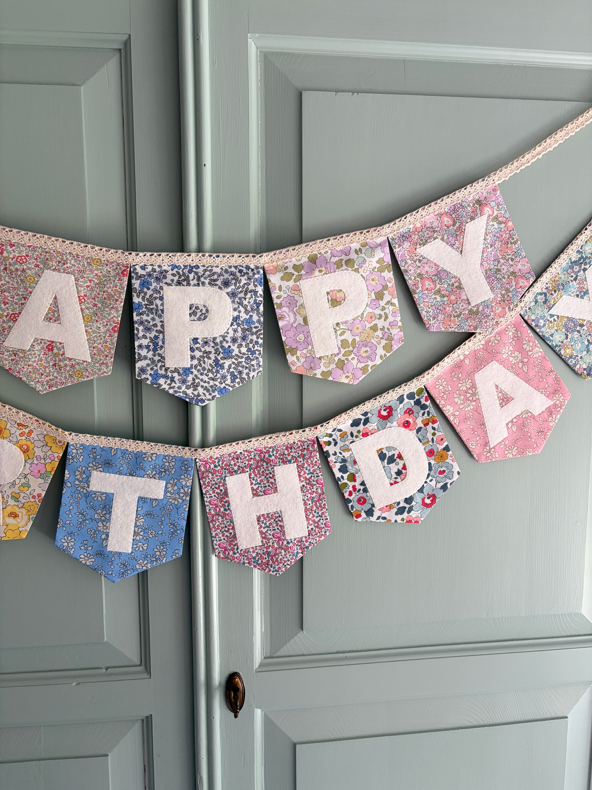 Close up of Liberty London Floral Print Bunting with ivory felt happy birthday applique letters