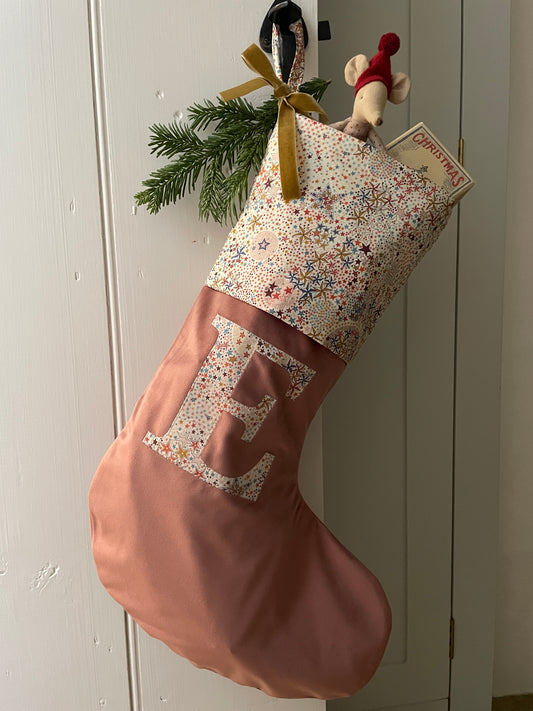 Dusty rose velvet stocking with a Liberty Print Tana Lawn Adelajda Brown fold over cuff and letter E appliquéd in. Full of toy gifts for Christmas 